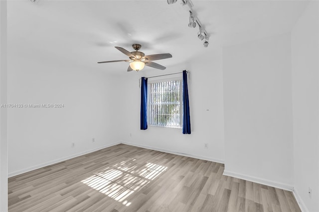 empty room featuring rail lighting, light hardwood / wood-style flooring, and ceiling fan