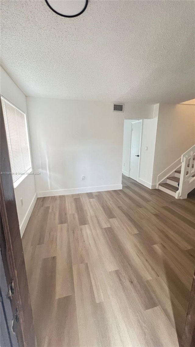 empty room featuring wood-type flooring and a textured ceiling