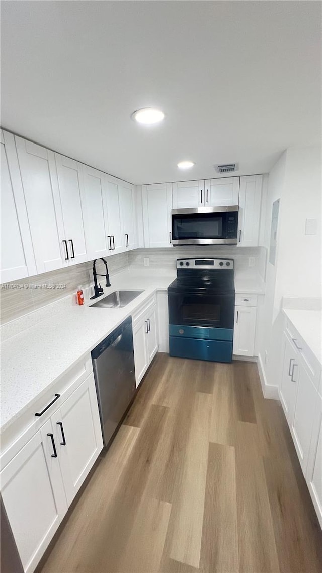 kitchen featuring white cabinets, light wood-type flooring, stainless steel appliances, and sink