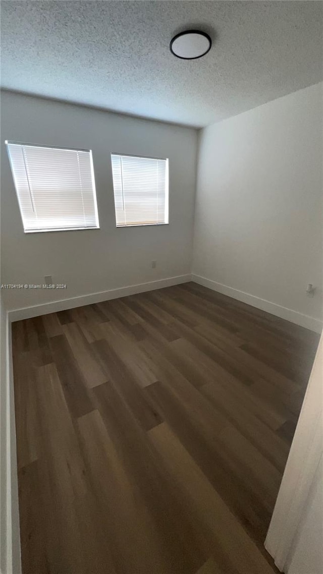 empty room with dark hardwood / wood-style flooring and a textured ceiling