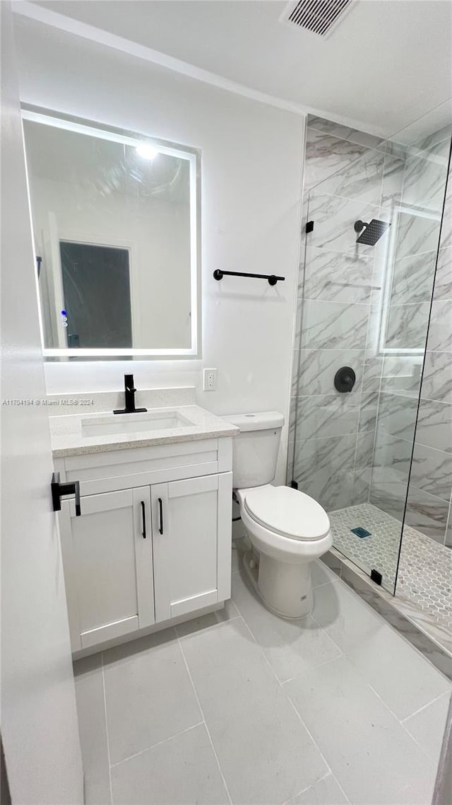 bathroom with tile patterned floors, vanity, toilet, and tiled shower