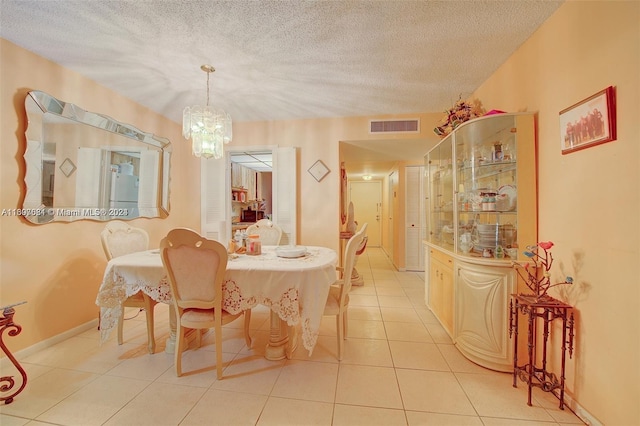 dining area with light tile patterned flooring, a textured ceiling, and a chandelier