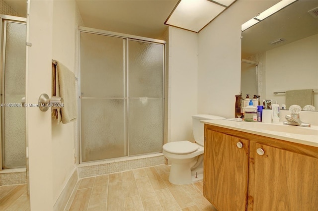 bathroom with hardwood / wood-style flooring, vanity, toilet, and an enclosed shower