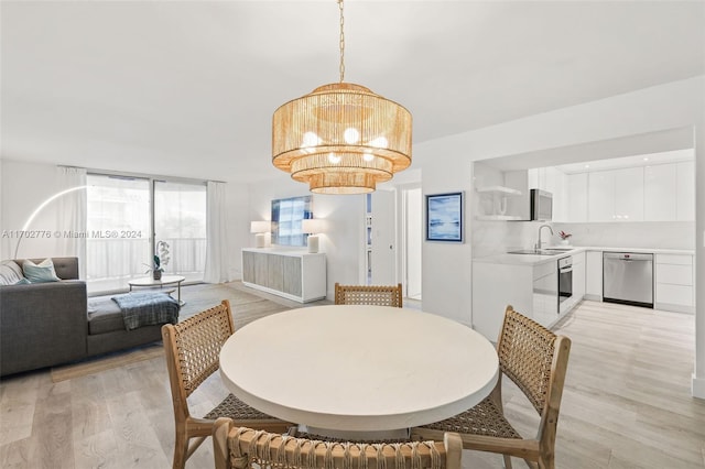 dining area with light hardwood / wood-style floors, sink, and a chandelier