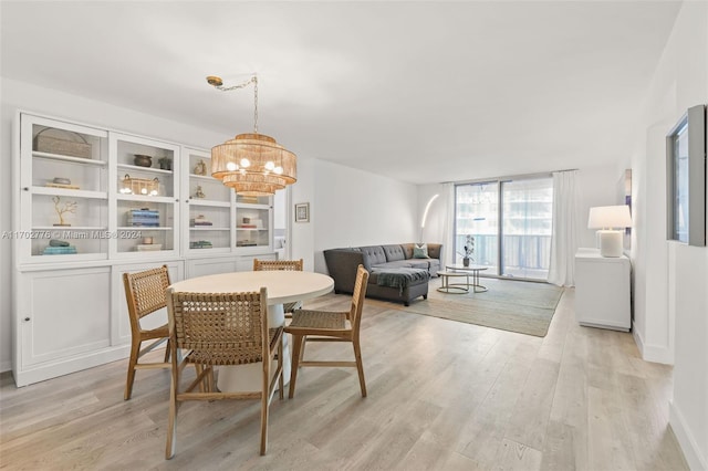 dining space with light wood-type flooring and an inviting chandelier