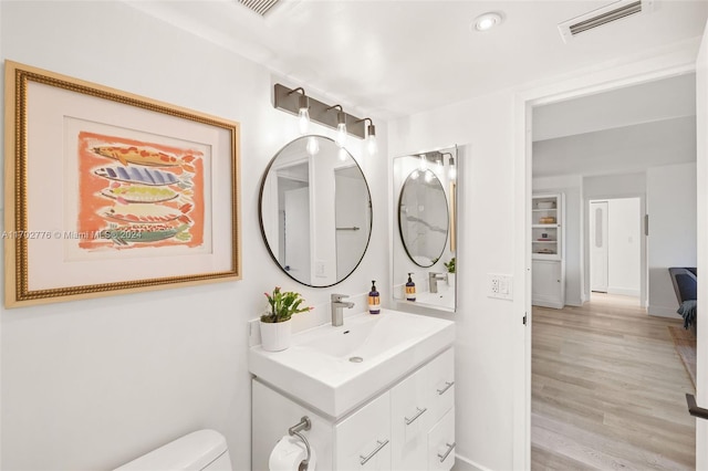 bathroom featuring toilet, vanity, and hardwood / wood-style flooring