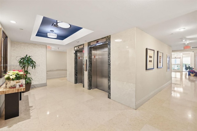 corridor featuring a tray ceiling and elevator