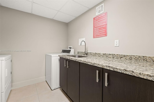 clothes washing area with light tile patterned flooring, cabinets, separate washer and dryer, and sink