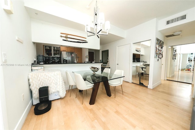 dining area with light hardwood / wood-style floors and a notable chandelier