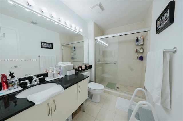 bathroom featuring tile patterned floors, vanity, toilet, and a shower with door