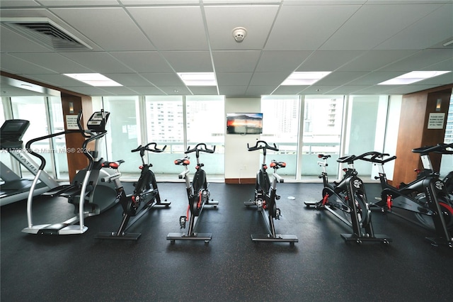 gym with a paneled ceiling and a healthy amount of sunlight