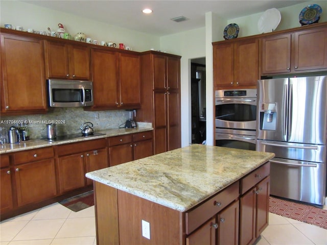 kitchen with a center island, decorative backsplash, light tile patterned flooring, light stone counters, and stainless steel appliances