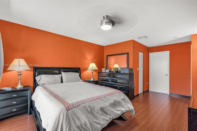 bedroom with hardwood / wood-style floors, a textured ceiling, and ceiling fan