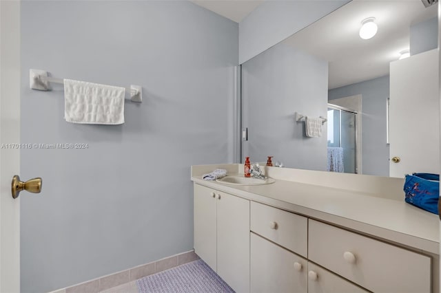 bathroom featuring tile patterned floors, a shower with door, and vanity