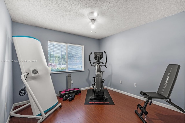 exercise room featuring a textured ceiling, dark hardwood / wood-style floors, and ceiling fan