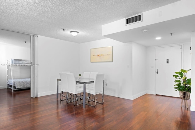 dining area featuring dark wood-type flooring and a textured ceiling