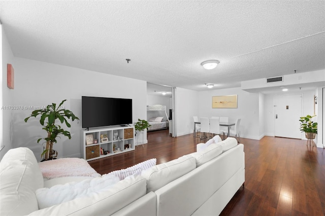 living room with a textured ceiling and dark hardwood / wood-style flooring