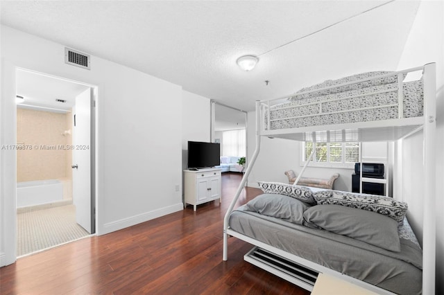 bedroom with dark hardwood / wood-style floors, a textured ceiling, and ensuite bath