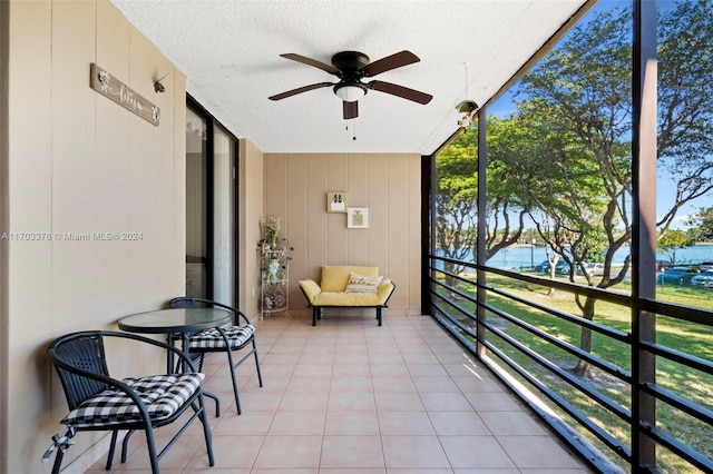 sunroom / solarium featuring a water view and ceiling fan