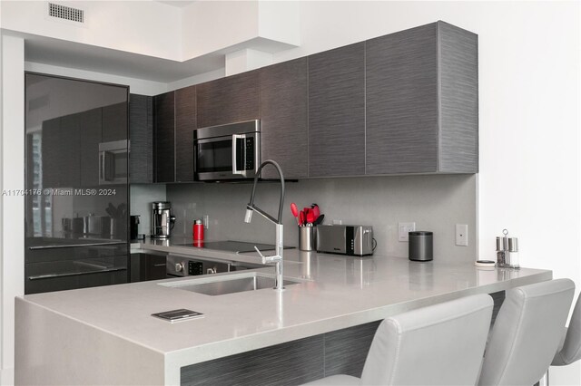 kitchen with dark brown cabinetry, kitchen peninsula, and sink