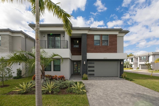 view of front of house featuring a balcony, a front lawn, and a garage