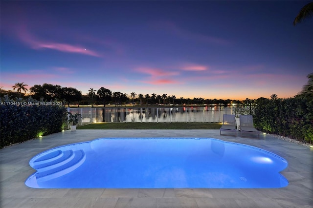 pool at dusk featuring a water view