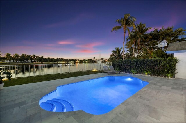 pool at dusk featuring a patio area and a water view