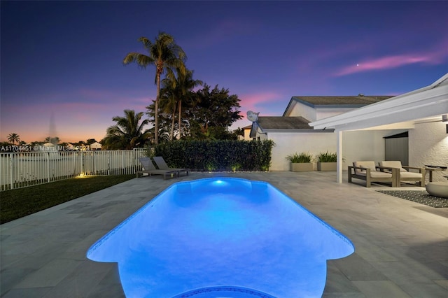 pool at dusk with a patio area