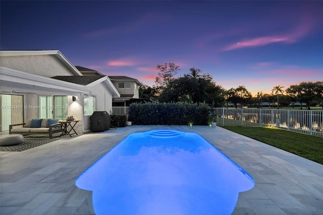 pool at dusk featuring area for grilling and a patio