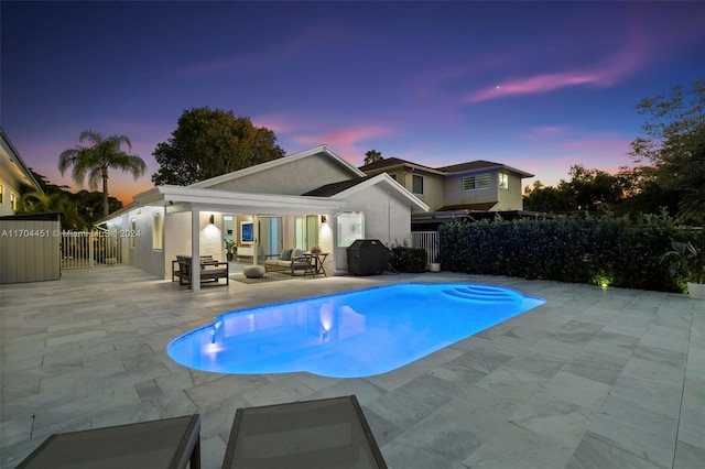 pool at dusk featuring an outdoor living space, a patio area, and grilling area