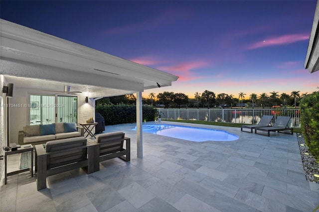 pool at dusk with an outdoor living space and a patio