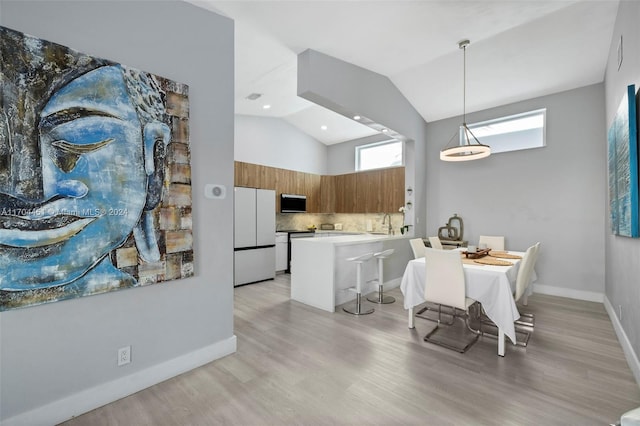 dining room with vaulted ceiling, light hardwood / wood-style flooring, and sink