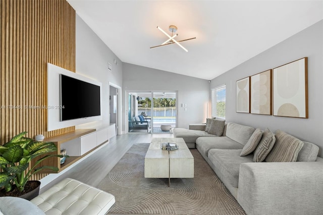 living room with hardwood / wood-style flooring, an inviting chandelier, and vaulted ceiling