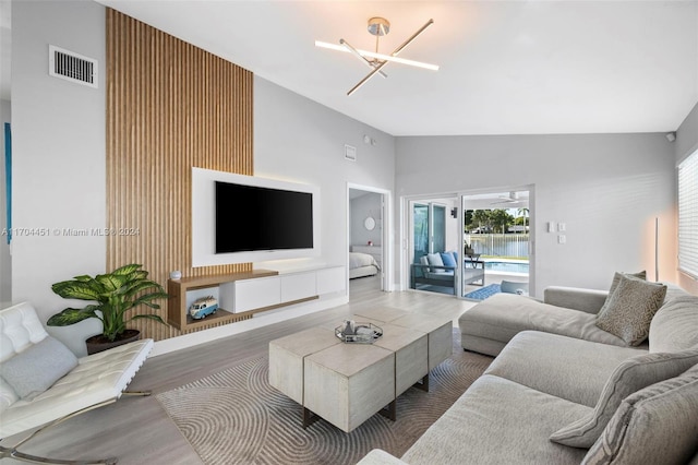 living room featuring hardwood / wood-style floors, high vaulted ceiling, and an inviting chandelier