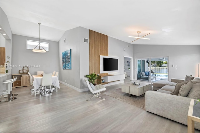 living room featuring a notable chandelier, light hardwood / wood-style floors, and vaulted ceiling