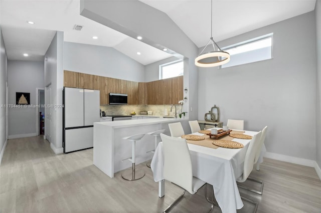 dining area featuring sink, high vaulted ceiling, and light wood-type flooring