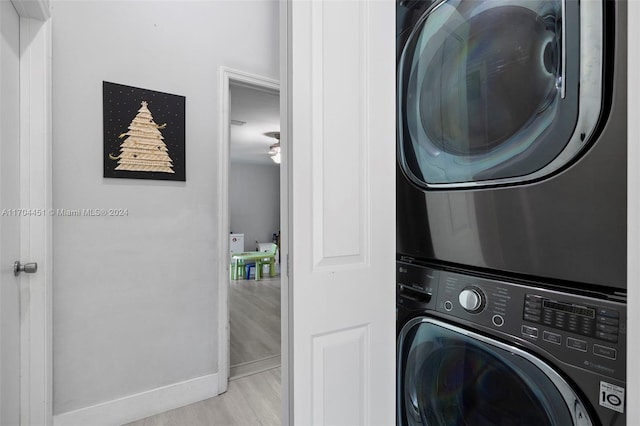 clothes washing area with light hardwood / wood-style flooring and stacked washer and clothes dryer