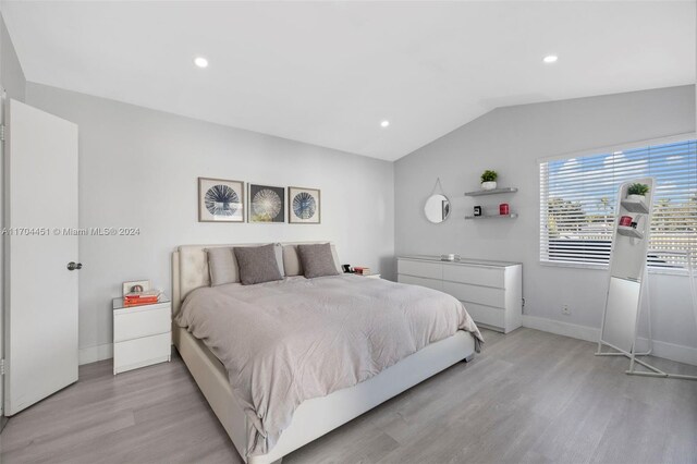 bedroom featuring light hardwood / wood-style floors and lofted ceiling