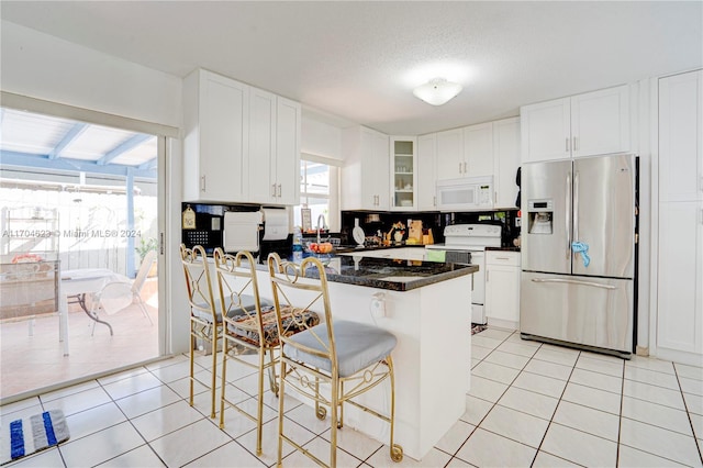 kitchen with white cabinetry, sink, white appliances, a kitchen bar, and light tile patterned floors