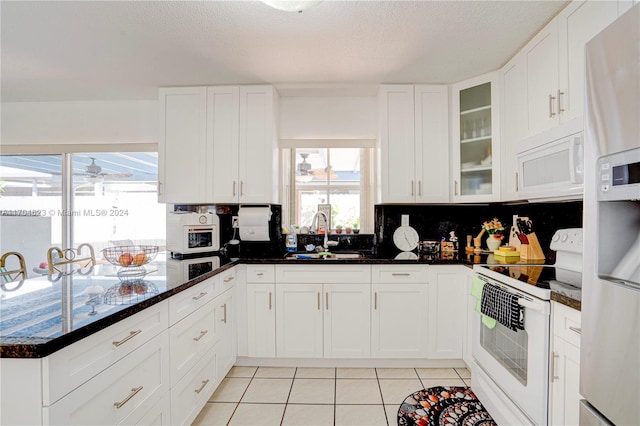 kitchen featuring decorative backsplash, white appliances, sink, white cabinetry, and light tile patterned flooring