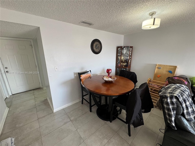 tiled dining room with a textured ceiling