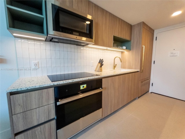 kitchen with sink, decorative backsplash, appliances with stainless steel finishes, light tile patterned flooring, and light stone counters