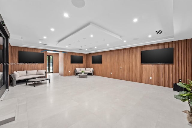 living room with a raised ceiling and wood walls