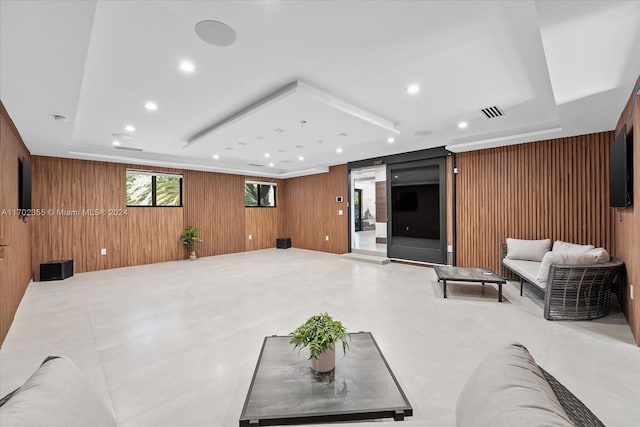 living room with a raised ceiling and wooden walls