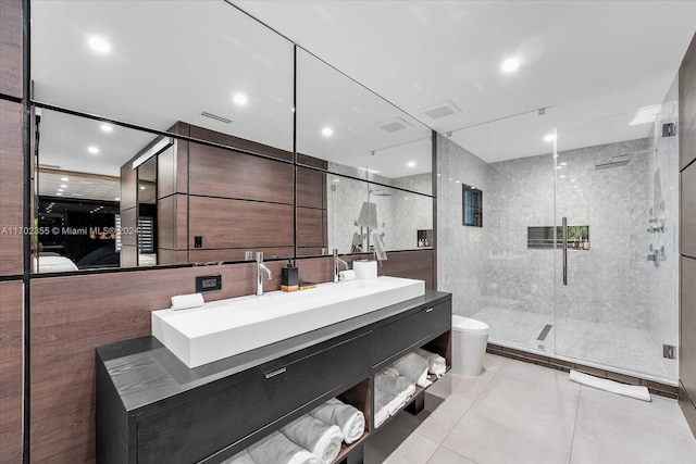 bathroom with tile patterned floors, vanity, tile walls, toilet, and a shower with shower door