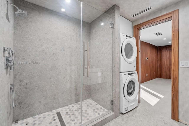 bathroom with stacked washer and dryer, concrete floors, and an enclosed shower