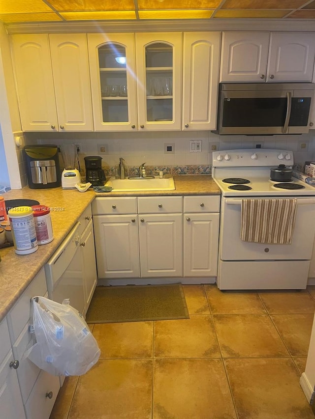 kitchen with white cabinetry, sink, tasteful backsplash, white appliances, and light tile patterned flooring