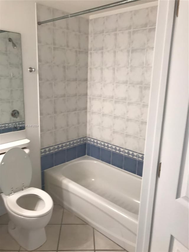 bathroom with tile patterned flooring, toilet, and tiled shower / bath