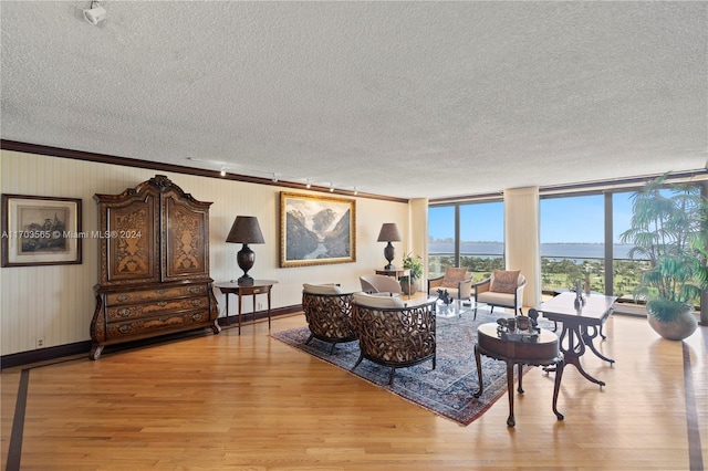 living room featuring floor to ceiling windows, crown molding, light hardwood / wood-style flooring, and a textured ceiling