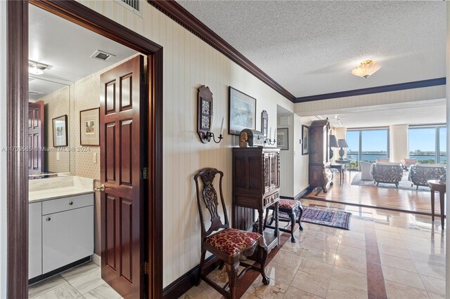 corridor with ornamental molding and a textured ceiling